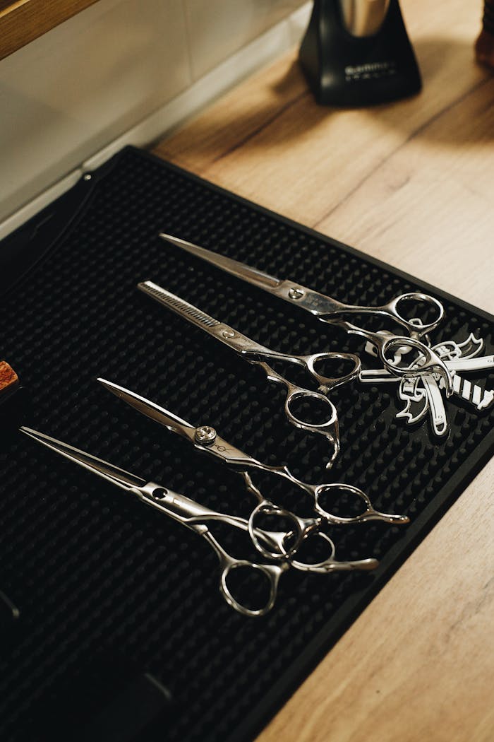 Close-up of a professional hairdressing scissors set on a black mat in a salon.